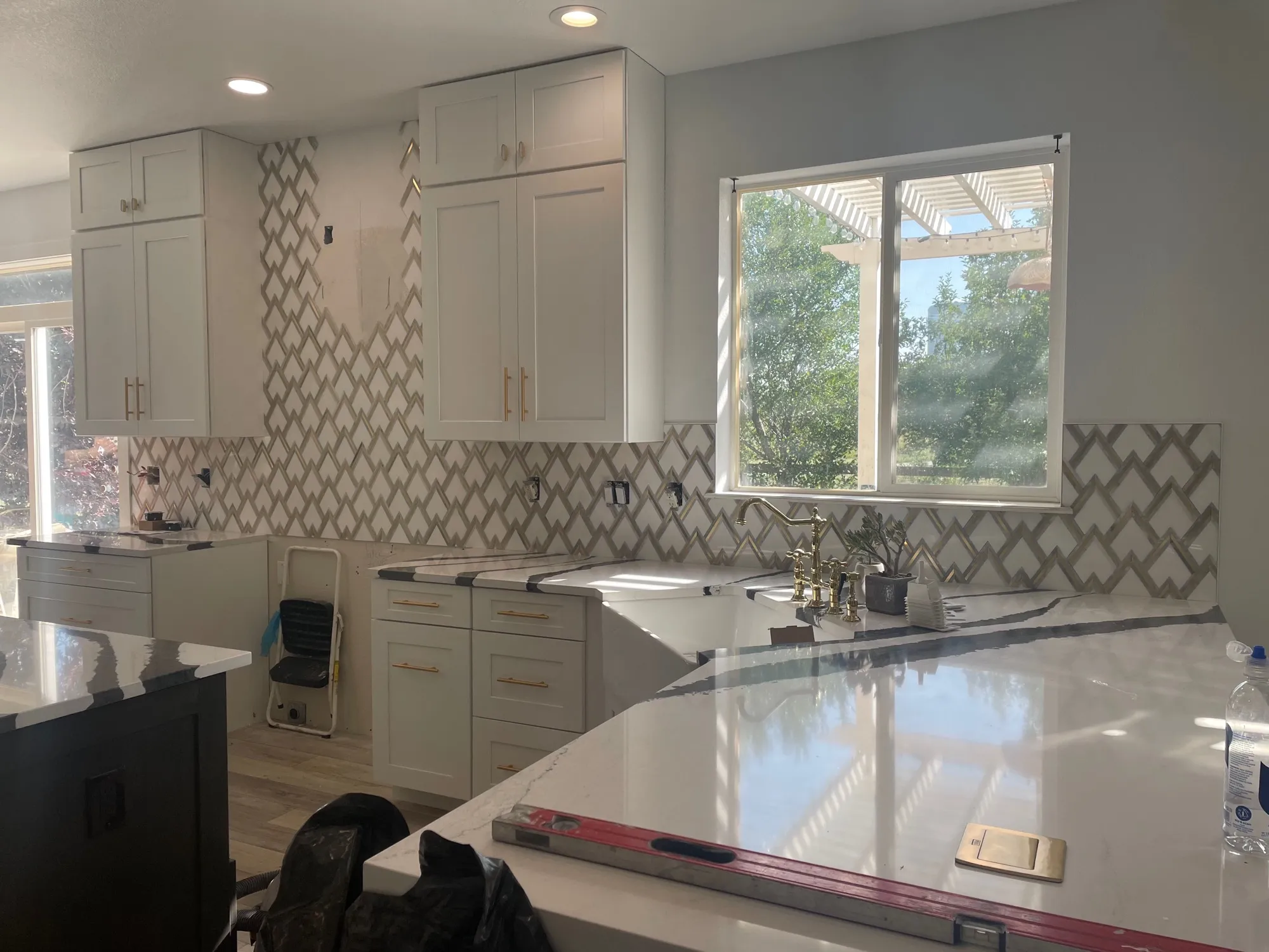 White-and-gray marble trellis mosaic backsplash with gold fixtures
