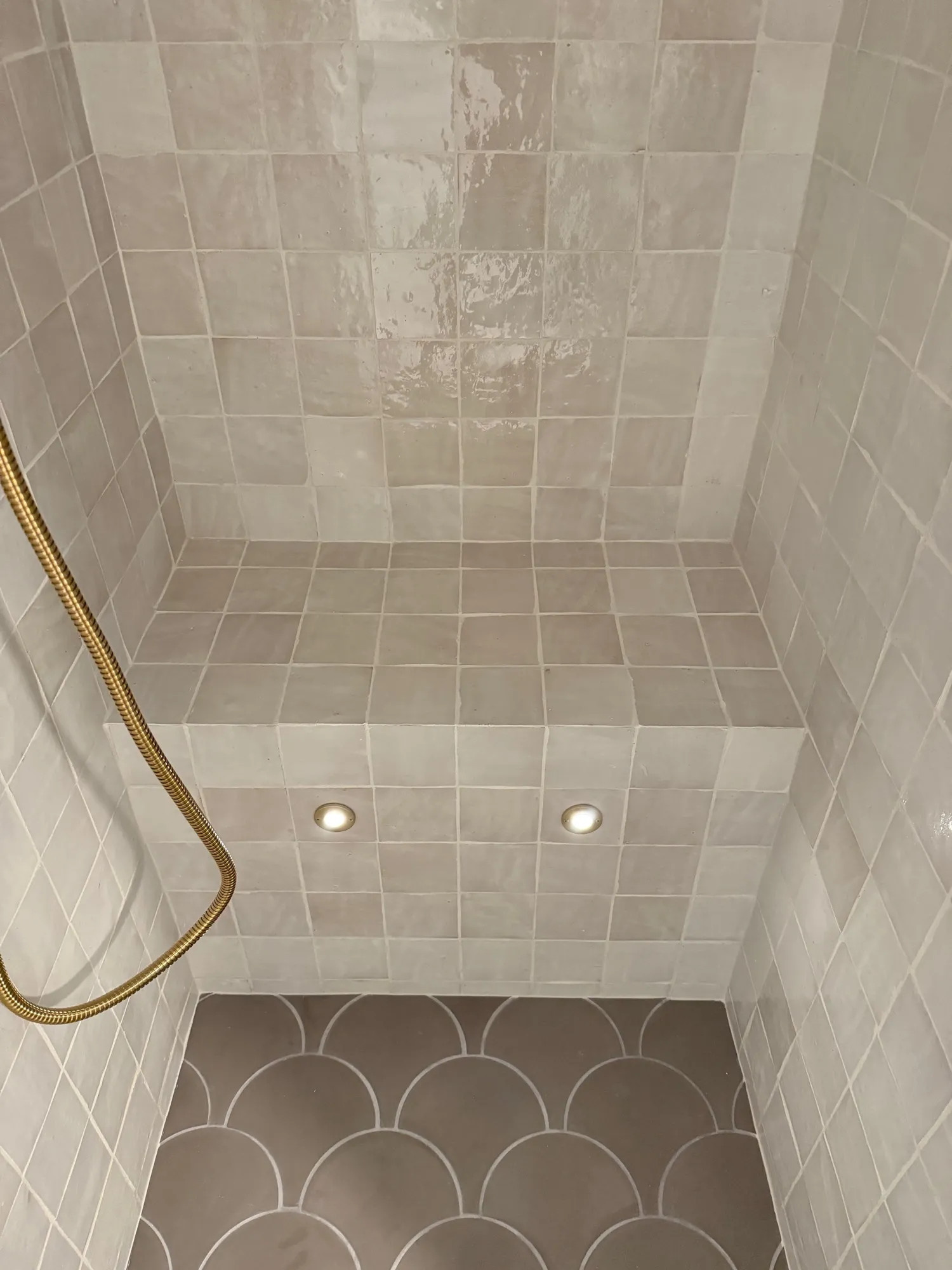 Cream zellige tile shower with a tiled bench and a gray scallop floor